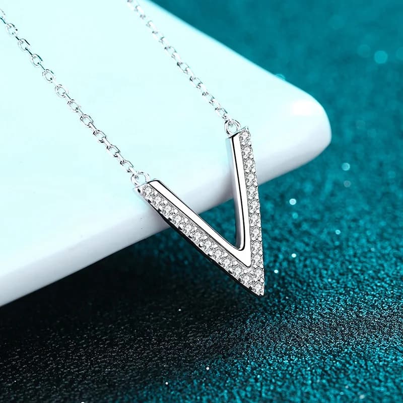 Crystal V pendant on a teal surface, made from iron and zinc alloy